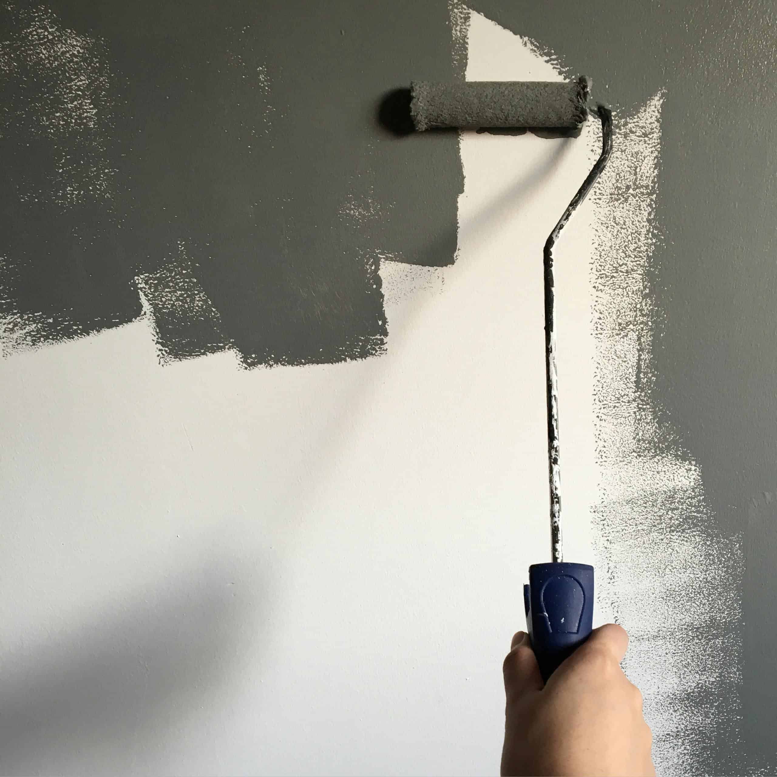 Hand painting a wall gray with a roller symbolizing voice refresh and update tips by The Working Voice